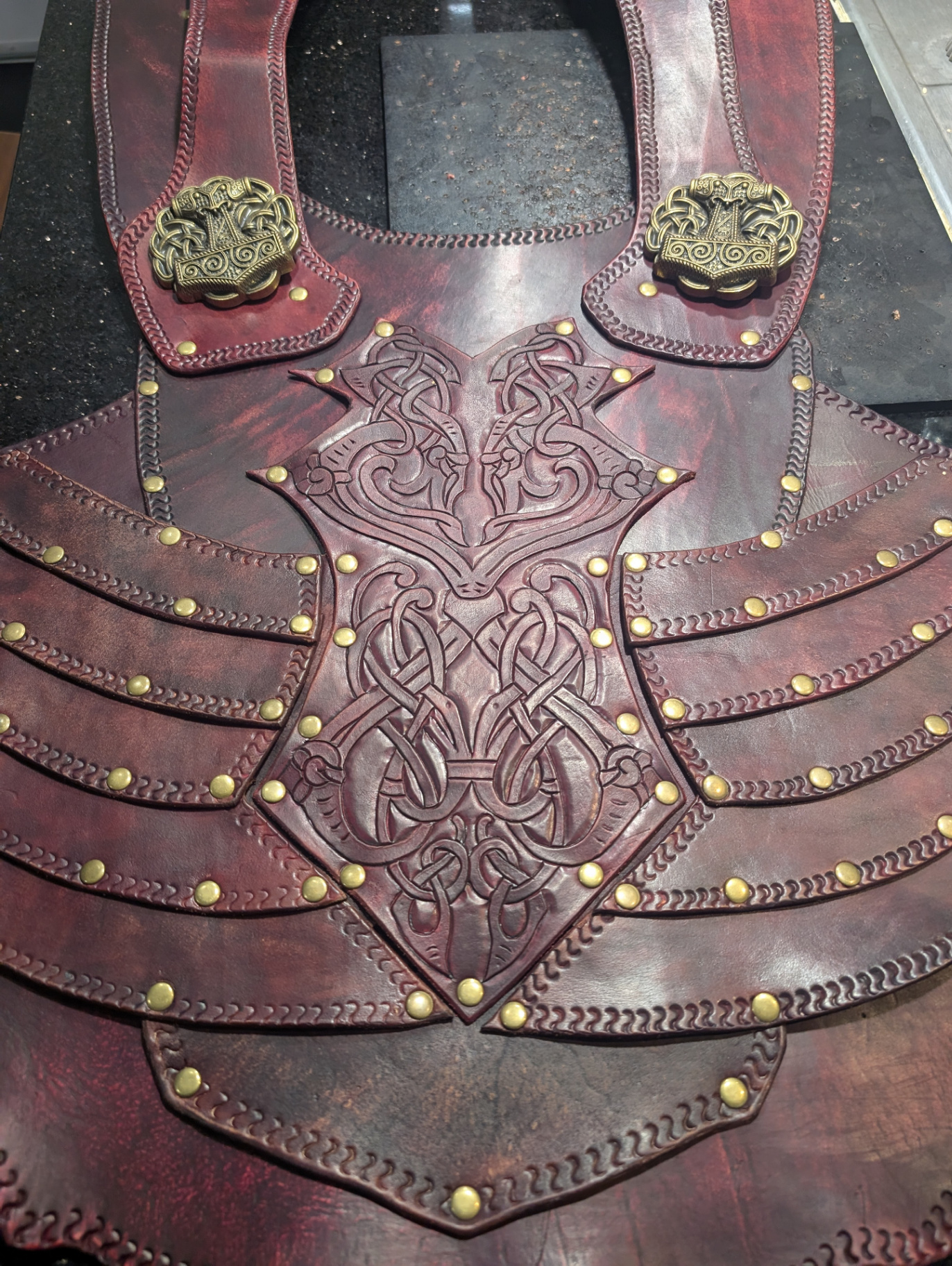 Full oxblood leather scale armor set with deep carved knotwork, Mjolnir conchos, and rows of brass-riveted scales