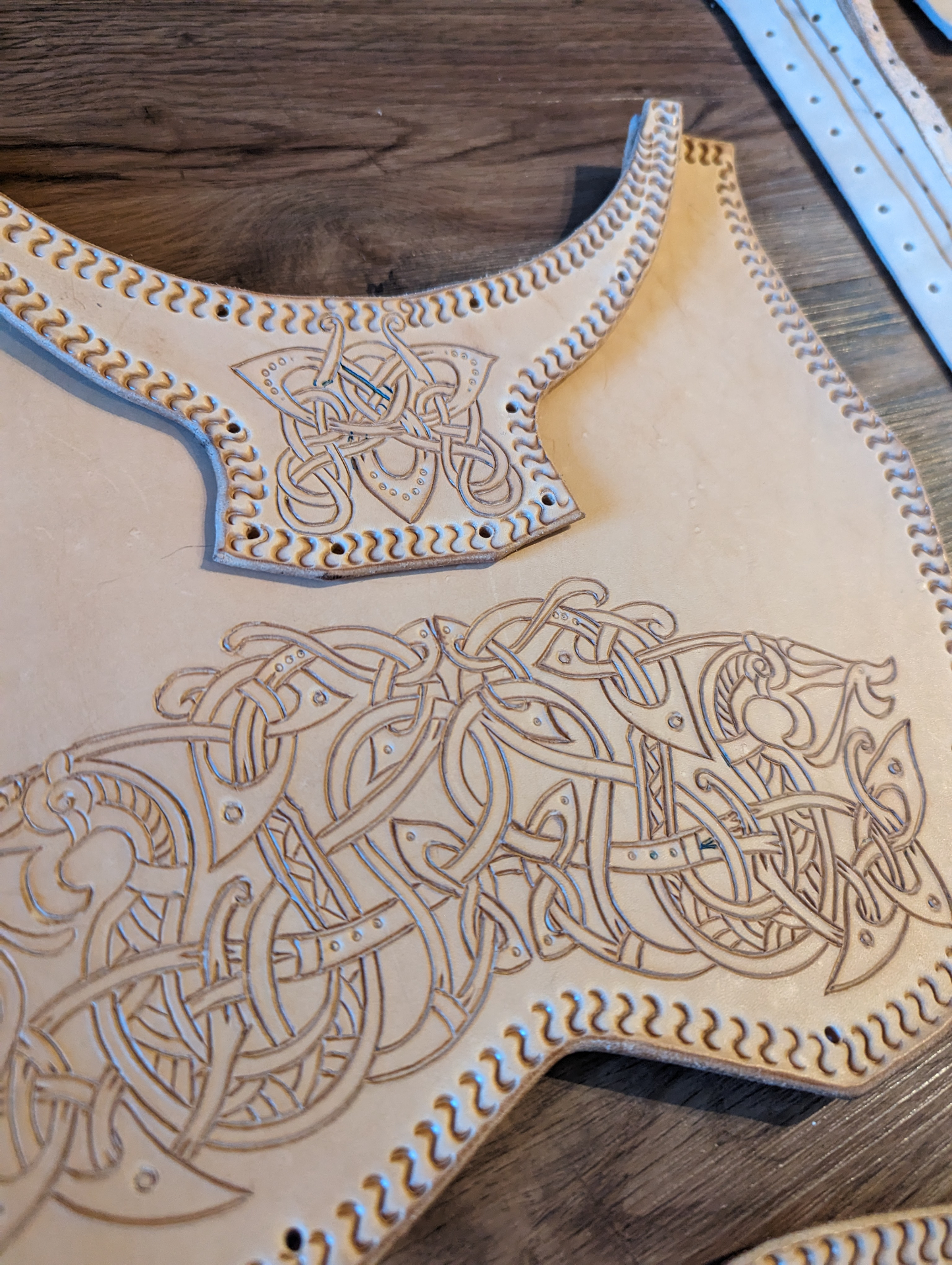 Close-up of etched knotwork and shoulder detailing carved into natural leather armor panels